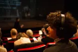 Une spectatrice malvoyante écoute une audiodescription des éléments visuels d'une représentation. L'audiodescription est réalisée par l'association Ecoute Voir, qui collabore avec des théâtres et compagnies de toute la Suisse romande. 